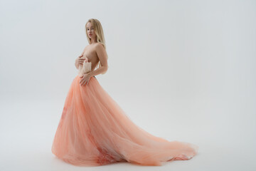 Fototapeta premium Blonde woman in elegant dress poses gracefully in a bright studio setting