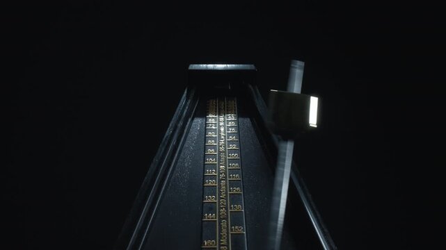 Vintage black metronome swinging back and forth