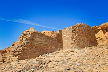 Part of Chaco Canyon Pueblo with a cliff and sky with clouds in the background, New Mexico.