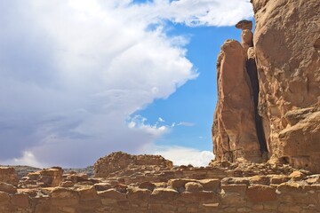 Part of Chaco Canyon Pueblo with a cliff and sky with clouds in the background, New Mexico.