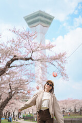 Woman tourist sightseeing Goryokaku Tower park with Sakura Cherry Blossom in Spring, happy traveler...