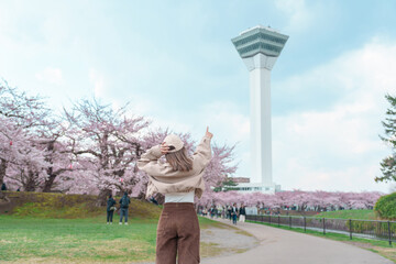 Woman tourist sightseeing Goryokaku Tower park with Sakura Cherry Blossom in Spring, happy traveler...