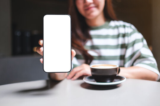 Mockup image of a woman holding and showing a mobile phone with blank white screen