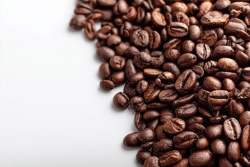 Obraz premium Pile of coffee beans on white backdrop with empty space on the left
