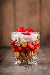 Greek yogurt, granola and strawberry on the rustic background. Selective focus.
