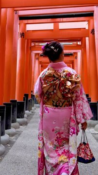 Vertical video Asian woman in traditional Japanese kimono at Fushimi Inari Shrine in Kyoto Japan.