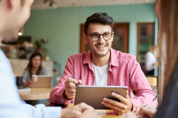 Man using tablet in cafe meeting with colleagues for business strategy discussion