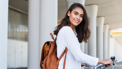 Portrait of a smiling woman with backpack riding bicycle in urban environment outdoors