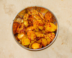 Top view of spicy fried potato slices served in a traditional steel bowl on a rustic background, homemade village food

