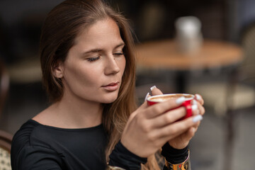 Woman Coffee Cafe: Young woman drinks coffee at an outdoor cafe for refreshment during the daytime.