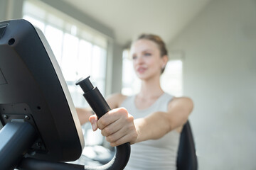 Fototapeta premium Woman, Bike, Exercising. Woman workout biking in gym. Young woman wearing sportswear exercising legs with bike machine