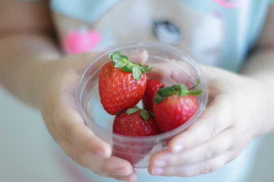 child holding strawberries - Powered by Adobe