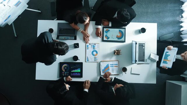 Top down aerial view of manager standing and present business plan to skilled investor. Business team working together to analyze financial statistic graph at meeting table. Time lapse. Directorate. - Powered by Adobe