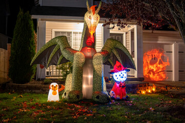 Glowing Halloween outdoor decorations with inflatable  dragon, ghost and orange skull projection on...