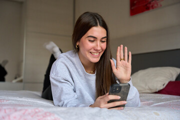 Happy female student making a video call from her bedroom
