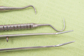 Sterile stainless steel dental instruments including explorer, dental mirror, and tweezer laid on...