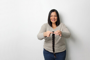 An adult Latina woman shows off the braid of hair she cut to donate for oncological wigs for girls...
