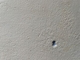 Close-up of a textured wall featuring a small hole.