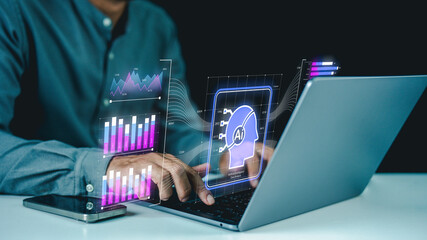 A person interacts with a laptop displaying futuristic AI and data analytics holograms in a dark...