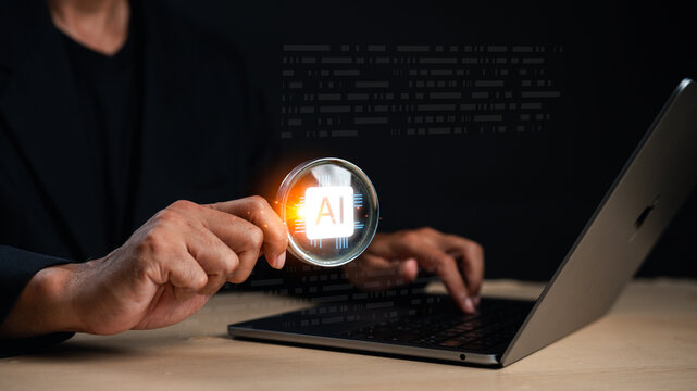 A person holds a magnifying glass over a laptop, highlighting the glowing "AI" symbol, symbolizing artificial intelligence and digital analysis.
