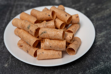 Crispy coconut rolls (Thong Muan) or Rolled Coconut Wafers in white plate.