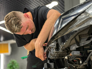 A car wrapping specialist applies a polyurethane film to the car. Detailer smoothes PPF. Car...
