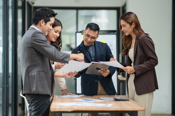 Group of business people are standing in a meeting presenting their work at the office.