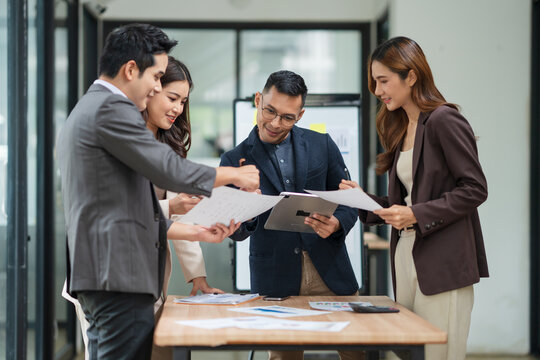 Group of business people are standing in a meeting presenting their work at the office.