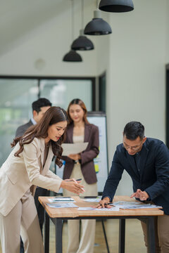 Group of business people are standing in a meeting presenting their work at the office.