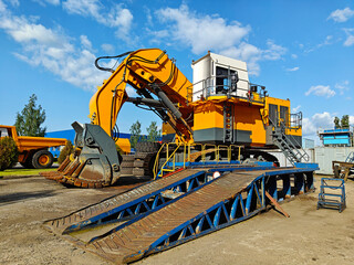 Large yellow excavator with a powerful digging arm, positioned on a construction site, surrounded...