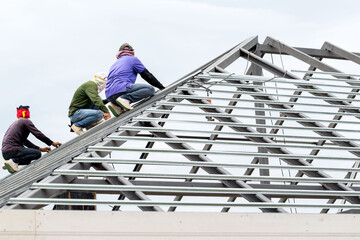 Three male construction labours sitting on building roof at building construction site no safety equipment. Labor cost and safety concept.