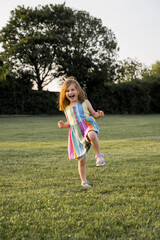 Happy little girl playing in the park at sunset