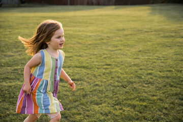 Little girl running in the park at sunset, copy space