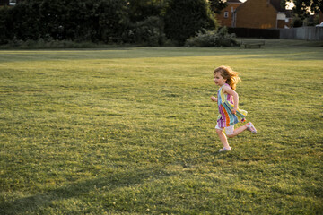 Little girl playing running in the park, sunset