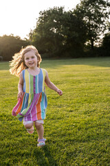 Little girl playing running in the park at sunset