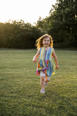Little girl running, playing in the park at sunset