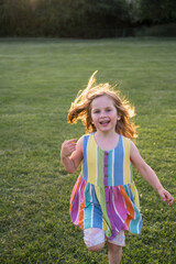 Little girl running, playing in the park at sunset