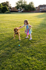 Toddler girl playing with a dog in the park