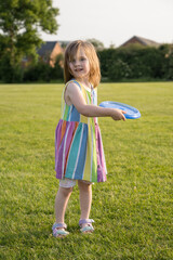 Little girl playing frisbee in the park, sunset