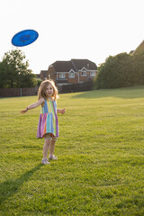 Little girl playing frisbee in the park, sunset