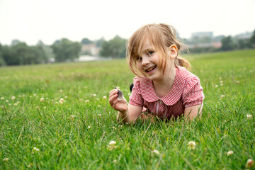 Cute little girl laying down on green grass in the park