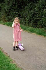 Little girl in the park with a scooter, werring school uniform