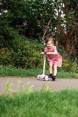Little girl riding a scooter in the park, outdoor activity