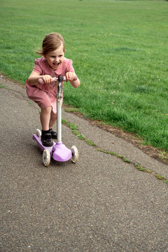 Little girl in the park riding scooter, wearing school uniform
