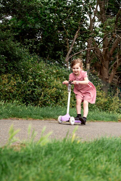 Little girl riding a scooter in the park, outdoor activity