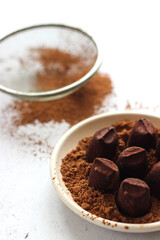 Truffle candies lie in a plate on a gray table