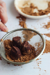 Truffle candies lie in a sieve on a gray table
