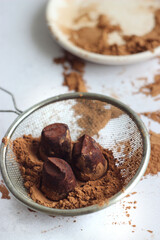 Truffle candies lie in a sieve on a gray table