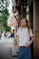 Fototapeta premium woman standing near building facade on city street in summer evening