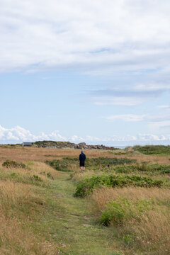 Young man walking in a field near coastline on sunny day